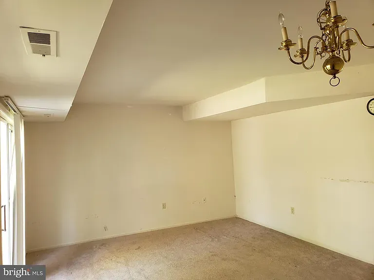 Carpeted living area with a chandelier and patio door