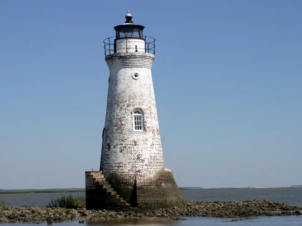 White brick lighthouse standing on a rocky tidal shoreline